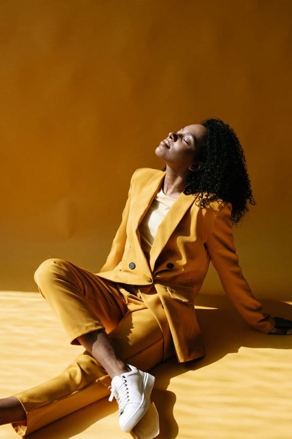 A warm yellow blazer and trouser set, seated in low sun