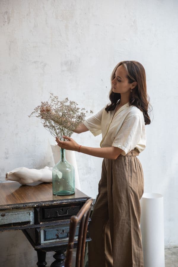 A linen shirt and wide trousers, arranging dried flowers